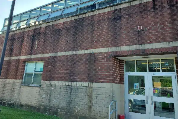 Before: A brick building exterior with a glass roof, featuring an entrance door and a grassy area in front.