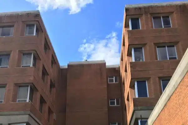 Before: Two red brick apartment buildings with windows, under a blue sky with white clouds.